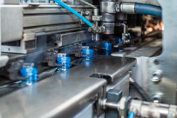 The newly blown plastic bottles come out of the blowing machine. Food production.