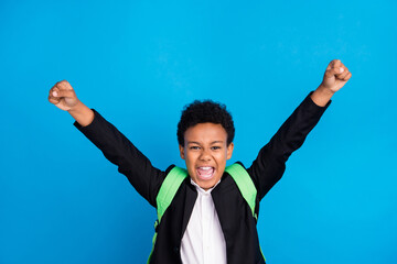 Photo of cheerful young happy positive boy raise fists winner good mood school isolated on blue...