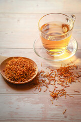 Cup of herbal tea with dried herb (lotus stamen) on wooden plate background.