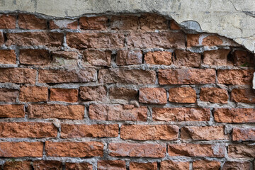 an image of an old red brick wall with fallen off plaster. the texture of the stone is visible.