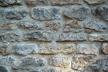 Part of the old stone wall is grey. The texture of the stone wall.