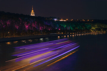 Fototapeta na wymiar A spacey view of a night traffic on the river and colourful street light on an embankment. 