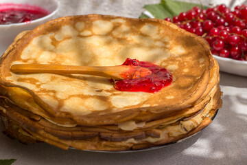 Spoon with red currant jam on a thin pancake. Traditional Russian food