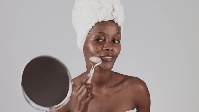 Black Woman makes face massage with jade roller