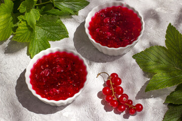 Two dishes with healthy red currant jam on a light table