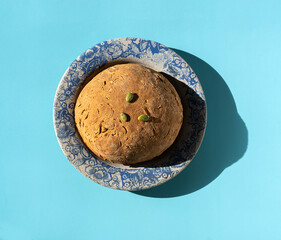Wheat-rye bread with pumpkin seeds on a ceramic plate with a pattern on the edge. Healthy food, yeast-free dough prepared at home. Top view, flat lay.
