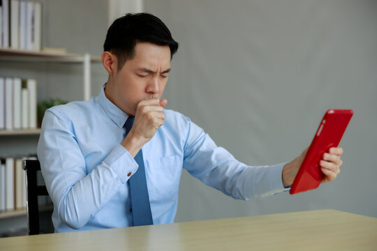 Business Man Coughing While Using Tablet And Talking Online With His Doctor From Office