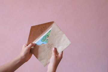 The child holds a paper envelope in his hand. letter for christmas. Letter to Santa Claus. Postal service. The girl wants to send or receive a letter. People communication concept. Christmas creative - obrazy, fototapety, plakaty