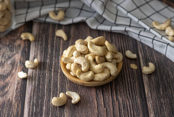 cashew nuts in a wooden plate and a checkered towel