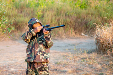 young hunter in a protective suit with a rifle getting ready to hit the target