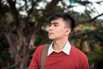 A young asian man spots something from afar. Looking sideways.