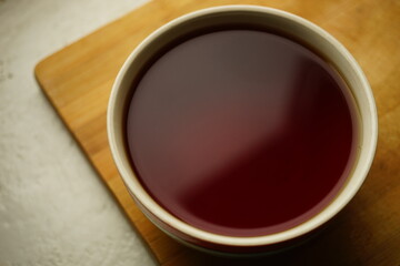 Large ceramic cup with black ceylon tea on wooden board