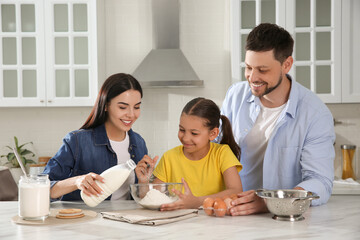 Fototapeta premium Happy family cooking together at table in kitchen. Adoption concept