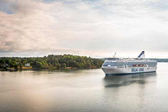 Stockholm, Sweden, 08.08.2021: Silja Line Symphony cruise ship at morning. Beautiful pink golden clouds. Panoramic View of Swedish coast from cruise ship. Ship passes through islands of archipelago.