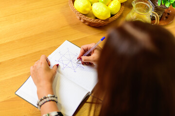 Girl draws the Matrix of Fate in a notebook, top view