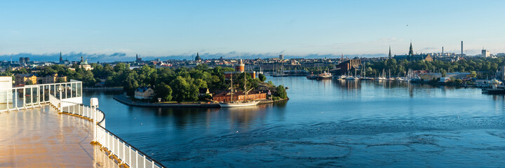 Naklejka premium Panoramic beautiful View of Stockholm Swedish capital from big modern cruise ship. Ship passes through the islands of archipelago. Towers of the buildings and city dominants are visible. Water trip.