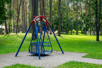 Swing for children with disabilities on wheelchair in city park on sunny summer day