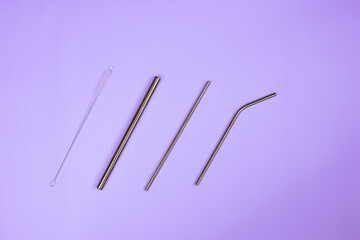 A set of drinking metal straws in a purple background