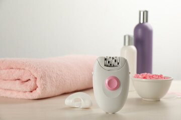 Obraz na płótnie Canvas Modern epilator and other hair removal products on white wooden table