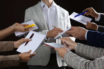 Man signing autograph in notebooks on black background, closeup