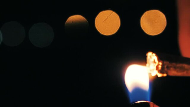 Joint getting lit at night in front of out of focus lights