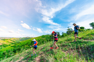 Three trail runners, a woman and an Asian man. Wearing runners, sportswear, practicing running on a dirt path in a high mountain forest. with a happy mood, on a clear day