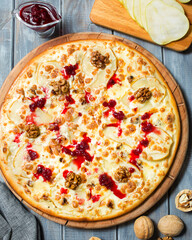 Italian cuisine. Pizza with pears, walnuts and gorgonzola. Sweet pizza with cheese and lingonberry sauce. Italian food on a wooden background. Fruit Pizza