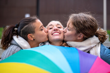 group of young homosexual women kissing, showing rainbow umbrella, symbol of the LGBT community,...