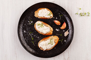 Fototapeta na wymiar Baguette slices with garlic spread on black plate.