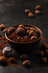 natural chocolate truffles in decorative dishes, dark background, gloomy mood