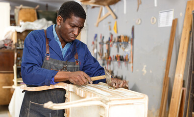 Portrait of furniture restorer in process of renewing vintage bureau at workshop