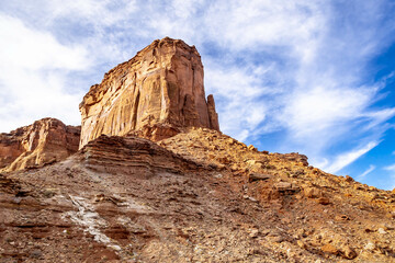 Looking up at a butte with wispy white clouds and a brilliant blue sky in Canyonlands National Park.