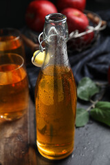 Delicious apple cider in glass bottle on black table