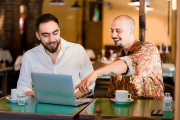 Two people using a laptop on a meeting at a coffee shop.