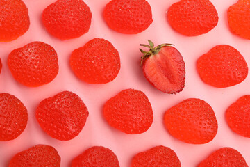 Delicious gummy candies and fresh strawberry on pink background, flat lay