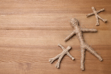 Voodoo dolls with pins on wooden table, flat lay. Space for text