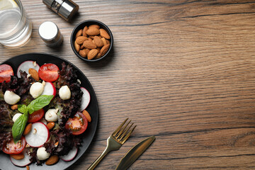Delicious vegetable salad with mozzarella served on wooden table, flat lay. Space for text