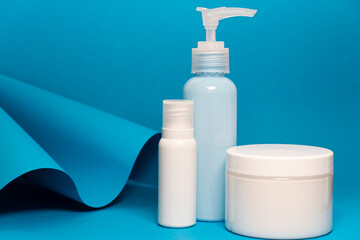 Art colourful geometry blue style and skin care cosmetics. Origami in a blue colour and cosmetics in white and blue colours: serum, face cream, face tonic. Paper mock up and luxury cosmetic. 