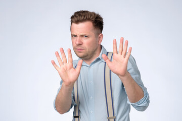 Young caucasian man saying stop showing denial gesture
