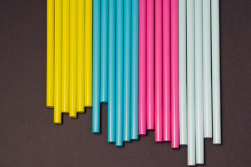 colourful cocktails straw for drinks in pink, yellow, blue colours on a dark background 