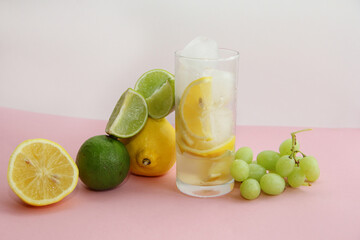cocktail with lemon, lime and min. lime and lemon on a pink background.lime slices and lemon in the cut