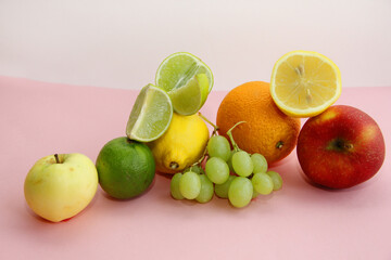 fresh fruit apple, lime, avocado, lemon, orange, grapes on a light pink background