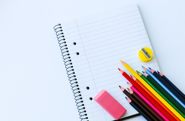 notebook in line with colored pencils with an eraser. sharpener on a white background