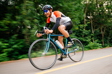 A man ride on bike on the road. Man riding vintage sports bike for evening exercise. A man ride bicycle to breathe in the fresh air in midst of nature, meadow, forest, with evening sun shining through