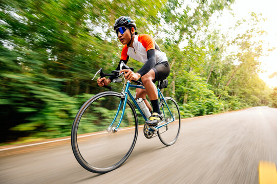 A man ride on bike on the road. Man riding vintage sports bike for evening exercise. A man ride bicycle to breathe in the fresh air in midst of nature, meadow, forest, with evening sun shining through