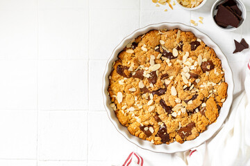 Homemade shortbread pie with milk and bitter chocolate in a baking dish on a white culinary background top view from a copy space. Delicious rustic sweet pastries	