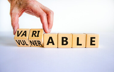 Vulnerable or variable symbol. Businessman turns wooden cubes and changes the word Vulnerable to...