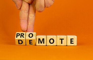 Promote or demote symbol. Businessman turns cubes and changes the word 'demote' to 'promote'. Beautiful orange background. Business, demote or promote concept. Copy space.