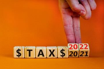 2022 tax new year symbol. Businessman turns wooden cubes and changes words 'Tax 2021' to 'Tax 2022'. Beautiful orange background, copy space. Business, 2022 tax new year concept.