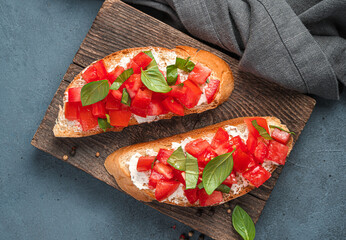 Two sandwiches with fried toast, tomatoes, cheese and basil on a gray-blue background.